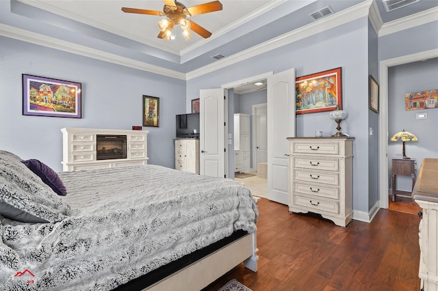bedroom with crown molding, baseboards, dark wood finished floors, and visible vents