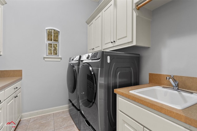 laundry room with washing machine and clothes dryer, cabinet space, a sink, baseboards, and light tile patterned flooring