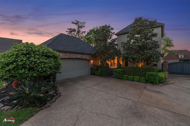 view of front of home featuring a shingled roof, a garage, stucco siding, a gate, and concrete driveway
