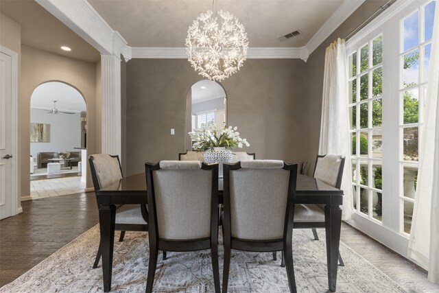 dining area featuring a healthy amount of sunlight, arched walkways, ornamental molding, and wood finished floors