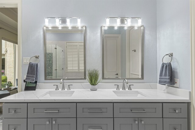 full bathroom with a sink, a stall shower, and double vanity