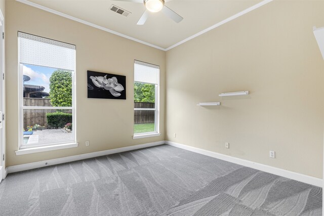 spare room featuring visible vents, ornamental molding, baseboards, a ceiling fan, and carpet