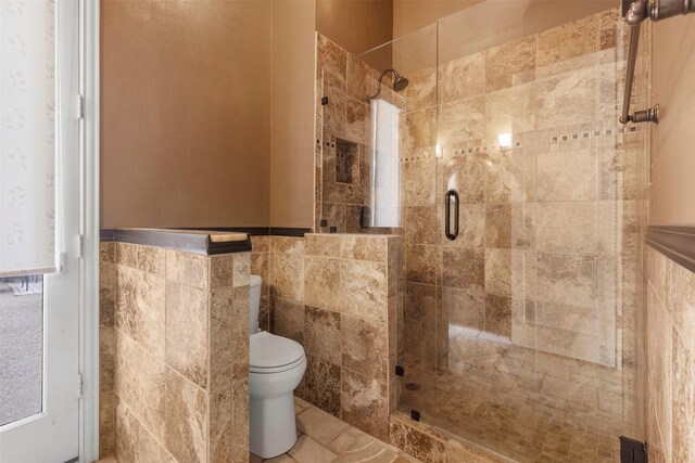 full bath featuring toilet, tile walls, and a stall shower