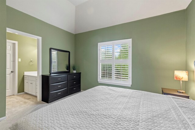 bedroom featuring baseboards, connected bathroom, lofted ceiling, and light carpet
