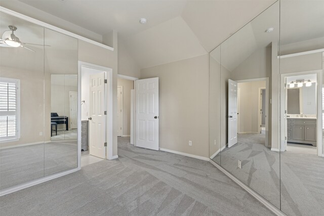 unfurnished bedroom featuring baseboards, lofted ceiling, and light colored carpet