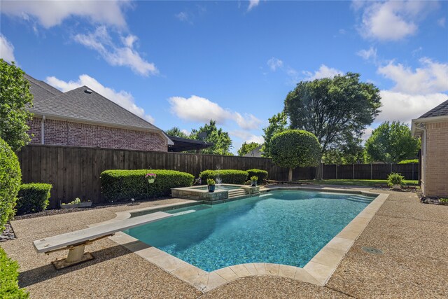 view of swimming pool featuring a diving board, a pool with connected hot tub, and a fenced backyard