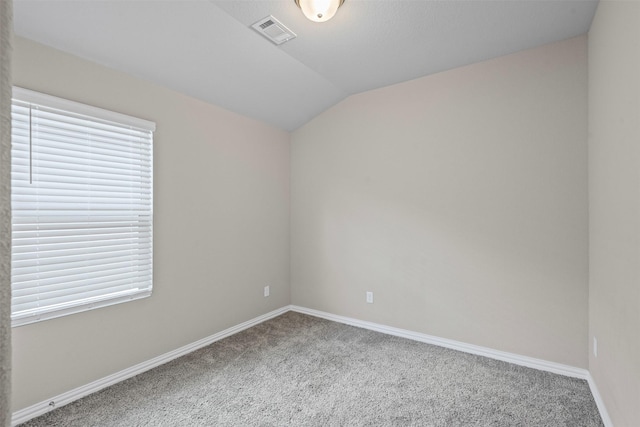 carpeted empty room featuring baseboards, visible vents, a wealth of natural light, and lofted ceiling