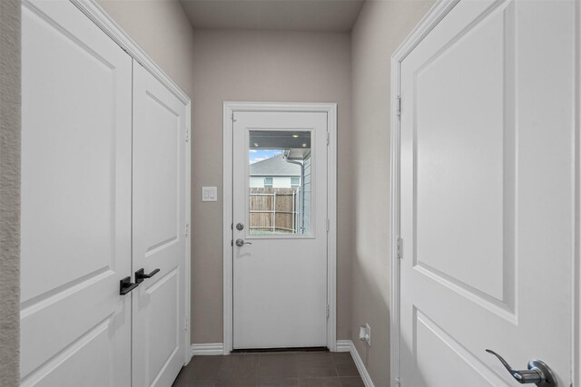 entryway featuring dark tile patterned flooring and baseboards