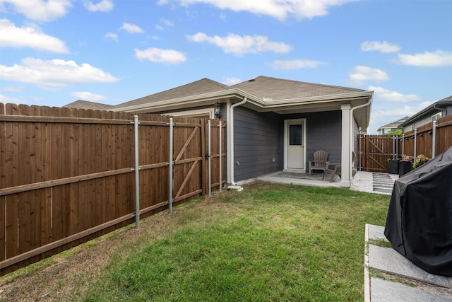 back of house with a gate, a fenced backyard, a yard, and a patio area