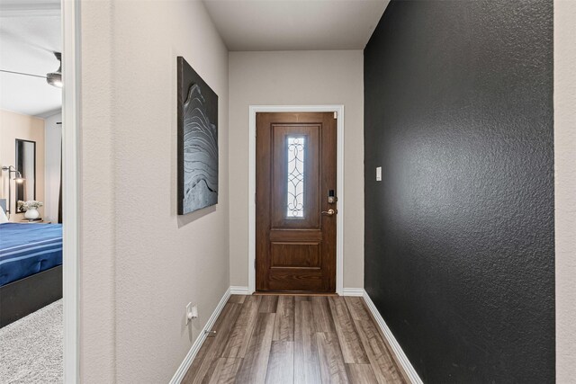 doorway featuring wood finished floors and baseboards