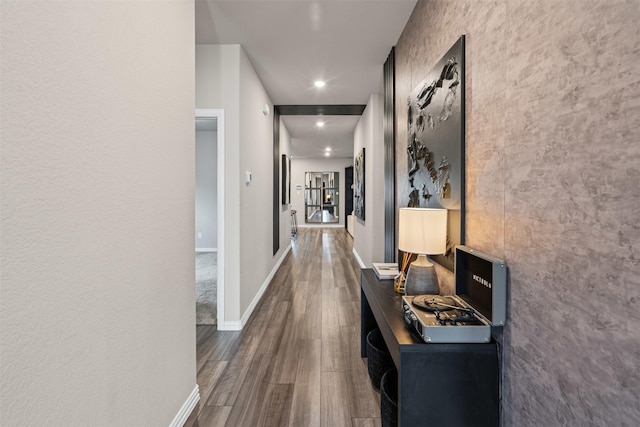 corridor featuring baseboards, recessed lighting, and wood finished floors