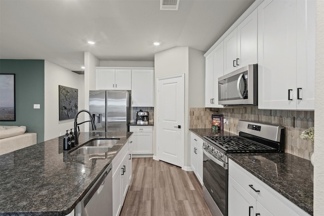 kitchen featuring white cabinetry, a sink, appliances with stainless steel finishes, light wood-style floors, and visible vents