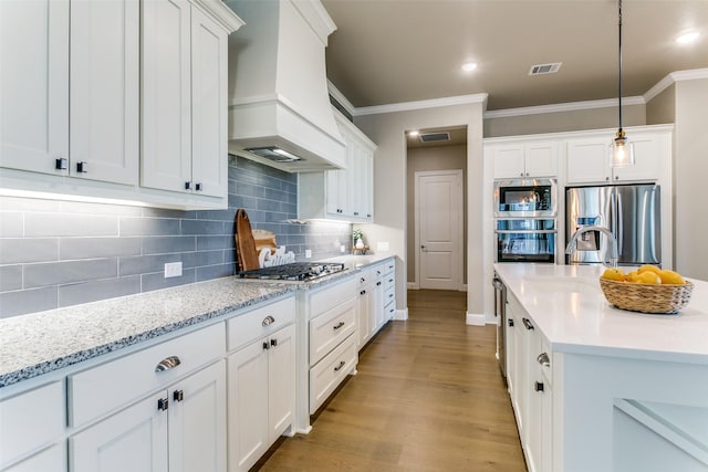 12492 Palmer Dr, Fort Worth, TX 76179 - kitchen with a sink, stainless steel appliances, custom range hood, visible vents, and ornamental molding