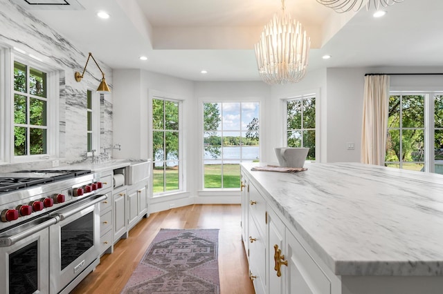 kitchen featuring recessed lighting, a notable chandelier, range with two ovens, light wood-type flooring, and white cabinetry