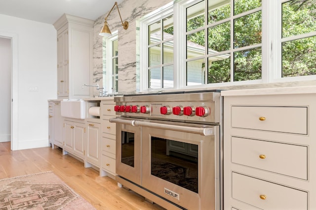bar featuring baseboards, light wood finished floors, and double oven range