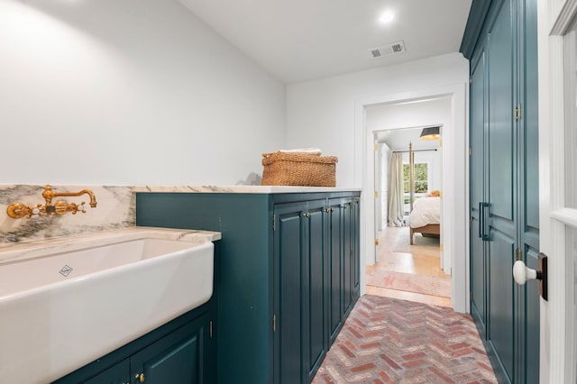 bathroom featuring visible vents, brick floor, and a sink