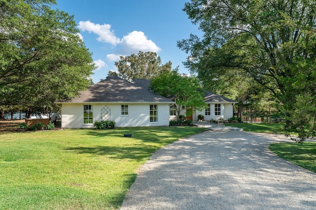 view of front of home with a front yard and gravel driveway