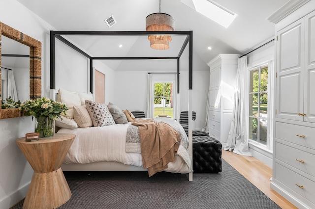 bedroom with lofted ceiling with skylight, visible vents, multiple windows, and light wood-style flooring