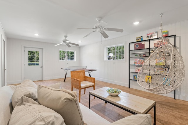 living room with baseboards, light wood-type flooring, recessed lighting, a decorative wall, and a ceiling fan