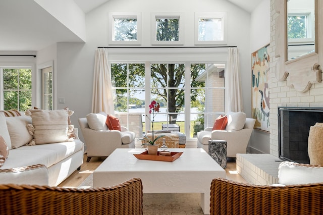 interior space with wood finished floors, high vaulted ceiling, and a brick fireplace