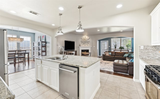 420 Westminster Dr, Lewisville, TX 75056 - kitchen featuring appliances with stainless steel finishes, a sink, a warm lit fireplace, open floor plan, and recessed lighting