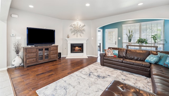 420 Westminster Dr, Lewisville, TX 75056 - living area featuring wood finished floors, baseboards, a warm lit fireplace, recessed lighting, and arched walkways