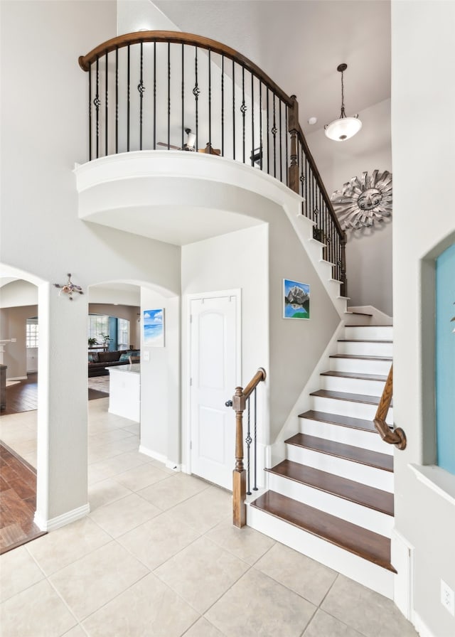 420 Westminster Dr, Lewisville, TX 75056 - staircase with arched walkways, a high ceiling, baseboards, and tile patterned floors