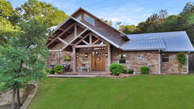 view of front facade with a front yard, metal roof, and stone siding