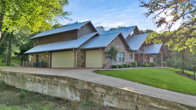 view of front of home featuring concrete driveway, metal roof, a front lawn, and stone siding