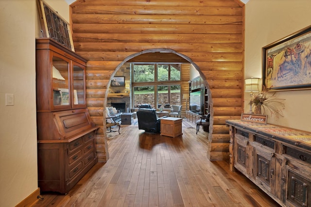 office area with a fireplace, log walls, hardwood / wood-style flooring, and arched walkways