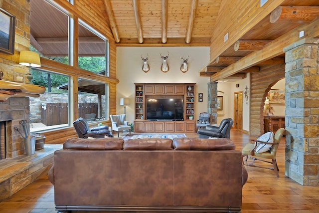 living area with beam ceiling, a towering ceiling, wood-type flooring, and wood ceiling