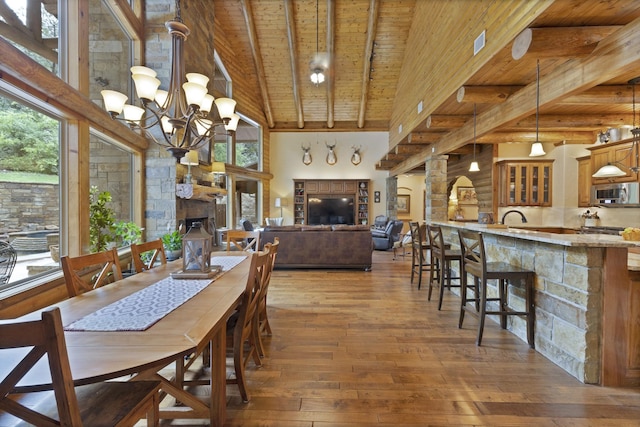 dining area with wood-type flooring, beamed ceiling, wood ceiling, and a fireplace