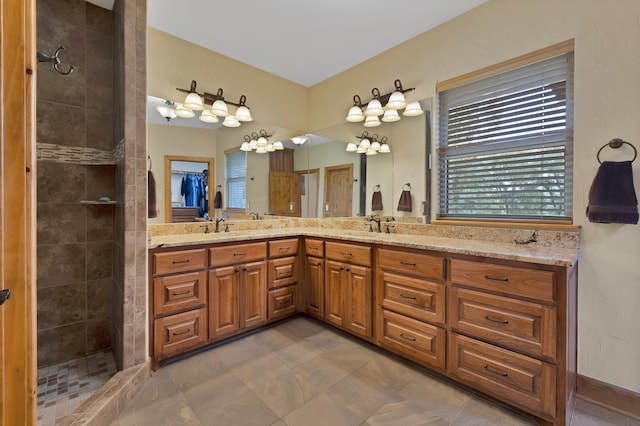 full bathroom featuring a sink, a tile shower, an inviting chandelier, and double vanity