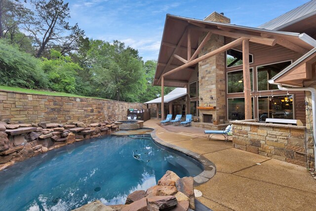 view of pool with an outdoor stone fireplace, a patio, and a fenced in pool