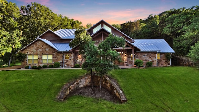 view of front of property with metal roof, a yard, and stone siding