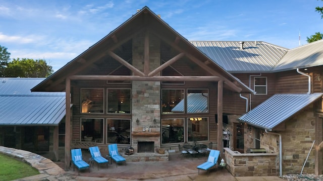 back of house with a patio, a large fireplace, metal roof, and stone siding