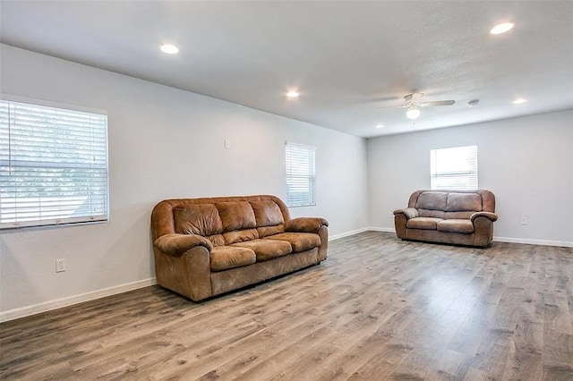living area featuring ceiling fan, a wealth of natural light, and wood finished floors
