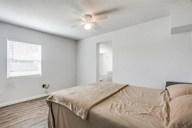 bedroom featuring a ceiling fan, ensuite bath, wood finished floors, and baseboards