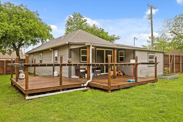 rear view of property with fence, a lawn, a shingled roof, and a wooden deck