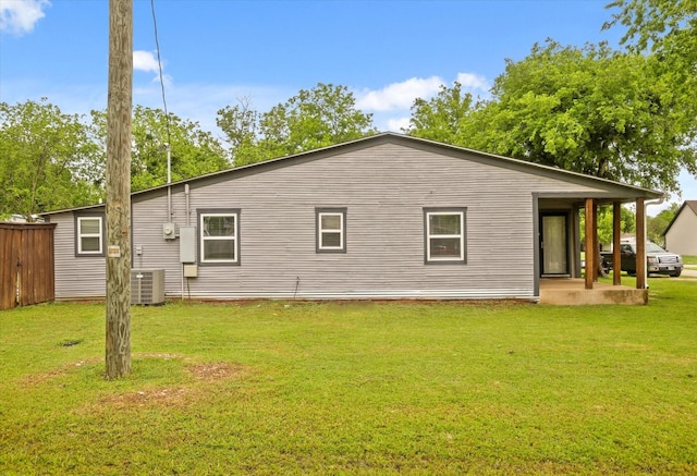 rear view of property with fence, a yard, and central air condition unit