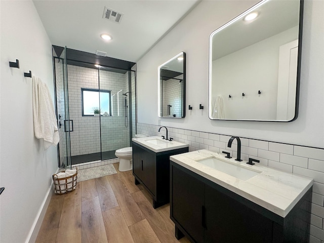 full bathroom featuring visible vents, wood finished floors, a shower stall, and a sink