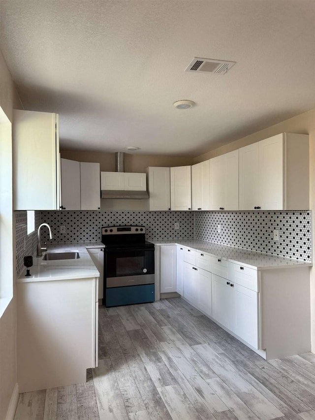 2726 Kellogg Ave, Dallas, TX 75216 - kitchen with light wood-style flooring, a sink, electric range, wall chimney exhaust hood, and backsplash