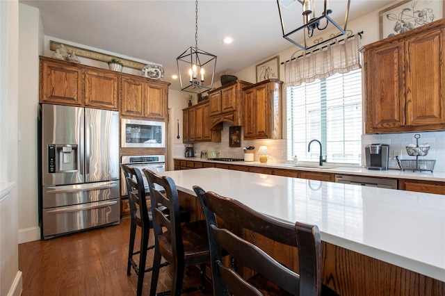 2621 Timberhollow Dr, Little Elm, TX 75068 - kitchen with an inviting chandelier, a sink, stainless steel appliances, brown cabinetry, and light countertops