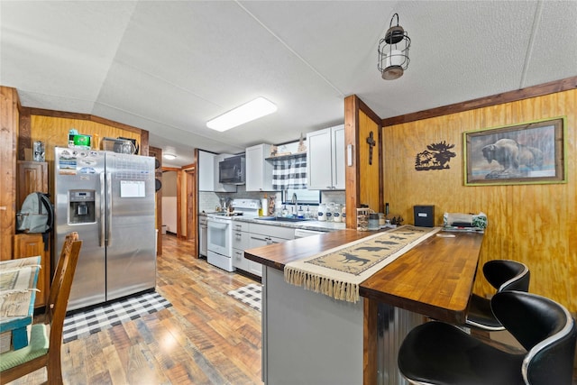 4991 Thunderbird Dr, May, TX 76857 - kitchen with a sink, black microwave, stainless steel refrigerator with ice dispenser, wood walls, and white stove