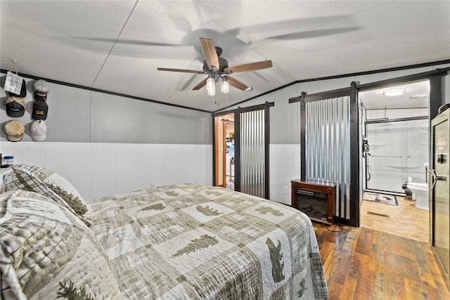 4991 Thunderbird Dr, May, TX 76857 - bedroom with a barn door, ceiling fan, wood finished floors, wainscoting, and lofted ceiling