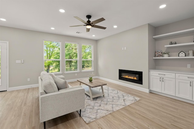 206 Splitrail Dr, Mabank, TX 75143 - living area with ceiling fan, a glass covered fireplace, visible vents, and light wood-type flooring
