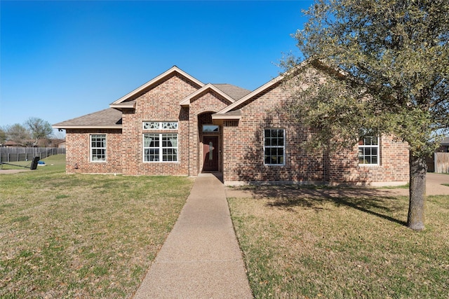 view of front of property featuring brick siding, fence, and a front yard