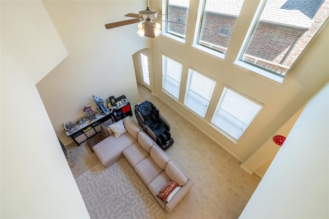 living room with a towering ceiling, ceiling fan, and a wealth of natural light