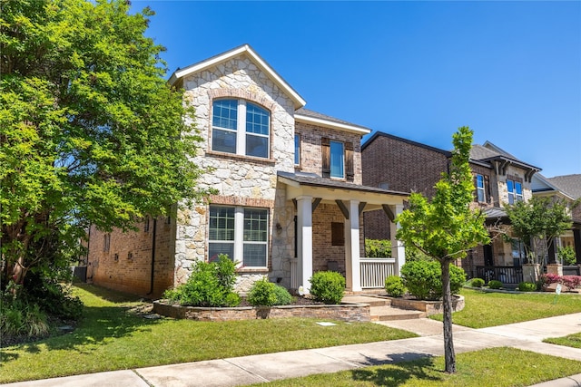 traditional home with brick siding, a front lawn, and stone siding