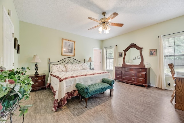 bedroom with baseboards, a ceiling fan, a textured ceiling, and wood finished floors